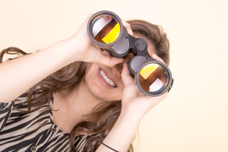 cute woman holding binoculars, yellow backgroundの写真素材