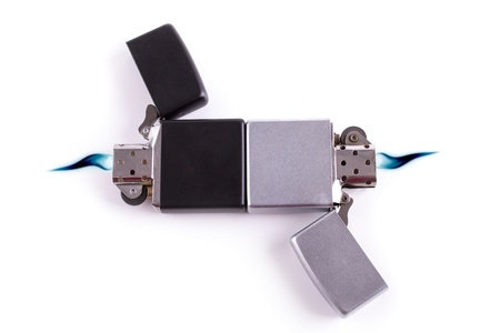 Silver metal lighters on white background with blue flame.の写真素材