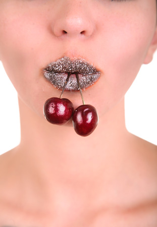 close-up portrait of beautiful girl's lower part of face with two red cherries in mouthの写真素材