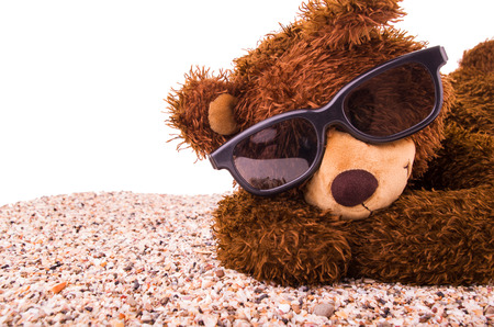 Teddy bear is sunbathing with beachsandの写真素材