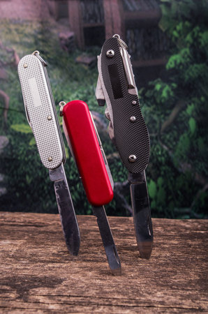 several swiss army knifes on wood in the rainforest