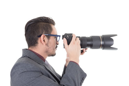 young man in suit taking a photo with professional camera isolated over whiteの写真素材