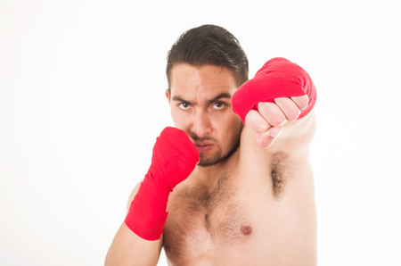 hispanic martial arts fighter wearing red shorts and wristband hitting isolated on whiteの写真素材