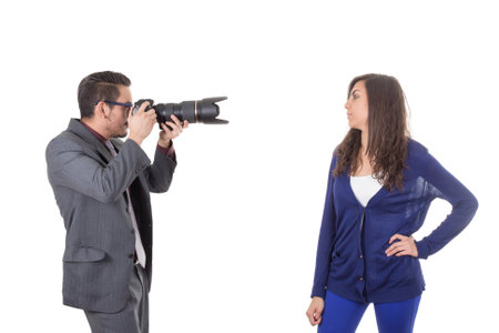 photographer shooting beautiful young girl dressed casually in blue isolatedの写真素材
