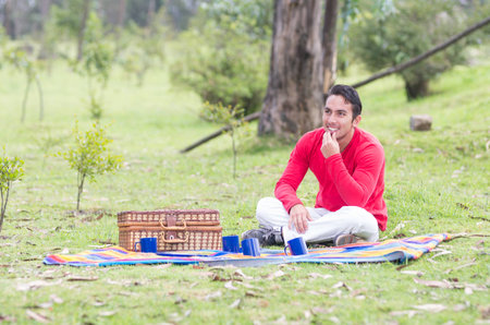 young man sitting having a picnic outdoorsの写真素材