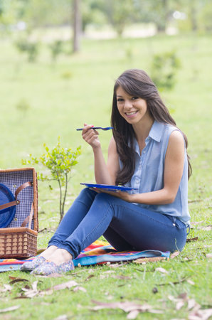 beautiful young girl eating having a picnic in a parkの写真素材