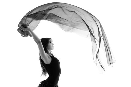Half body shot of young beautiful ballerina dancing with a flying veil isolated on white in black...
