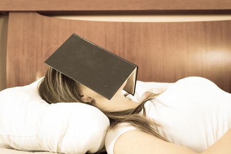 Young girl sleeping with book on her face color tonedの写真素材