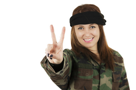 Young happy girl dressed in green camouflage jacket gesturing peace with fingers isolated on whiteの写真素材