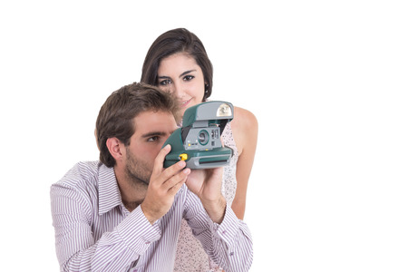Beautiful girl and attractive man taking photos with vintage instant camera isolated on whiteの写真素材