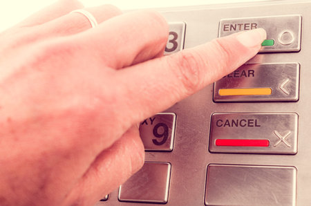 Closeup of finger using atm machine with metallic keyboard