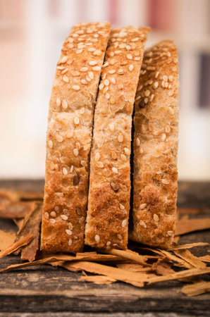 standing slices of whole bread with sesame seeds on wooden table