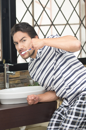 handsome young man brushing his teeth in modern bathroomの写真素材