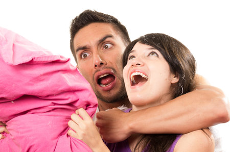 cute playful couple having a pillow fight isolated on white
