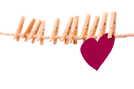pinks paper heart and many clothespins hanging on a rope clothesline isolated on whiteの写真素材
