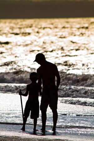 Father and son silhouettes enjoying the beach at sunset in Same, Ecuadorの写真素材
