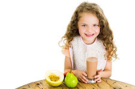 Cute little happy preschooler girl holding a glass of chocolate milk isolated on whiteの写真素材