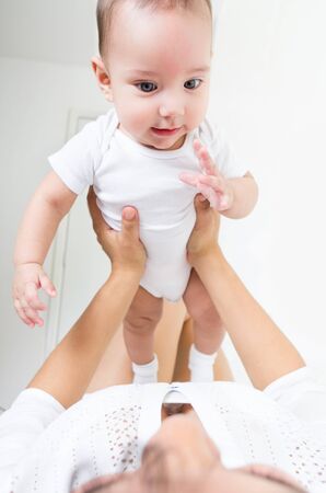 Closeup portrait of sweet baby boy being held by her mother low angleの写真素材