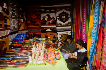 OTAVALO, ECUADOR - FEBRUARY 27, 2010: Unidentified indigenous couple in a colorful textile stall in the popular Otavalo market.のeditorial素材