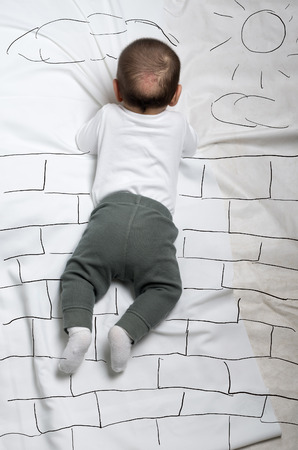 Cute infant baby boy climbing brick wall sketchの写真素材