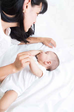 loving mother looking at her adorable baby boy sleeping, over the shoulder shotの写真素材