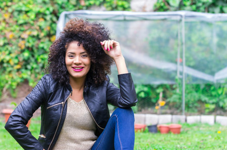 exotic beautiful young girl with dark curly hair relaxing in the gardenの写真素材