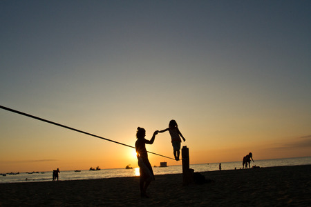 Silhouette of little girl balancing on slackline during sunset at a beach in Manabi, Ecuadorの写真素材