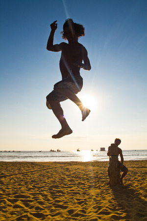 MANABI, ECUADOR - JUNE 5, 2012: Silhouette of young man balancing jumping on slackline during sunset at a beach in Manabiのeditorial素材