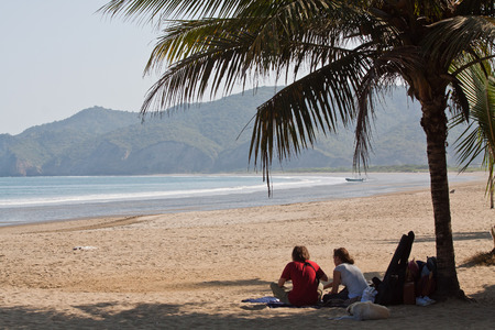 MANABI, ECUADOR - JUNE 6, 2012: Unidentified tourists relaxing under a palm tree in a peaceful beachのeditorial素材