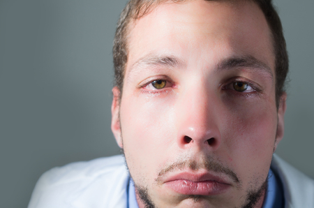 Closeup portrait of sad young doctor crying over gray backgroundの写真素材