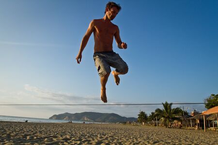 MANABI, ECUADOR - JUNE 5, 2012: Silhouette of young man balancing jumping on slackline during sunset at a beach in Manabiのeditorial素材