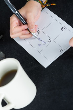 hand writing on paper calendar date 21 next to coffee mugの写真素材