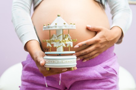 caption of pregnant standing up and hands holding small carouselの写真素材
