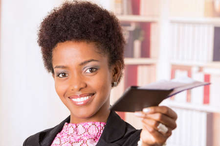 Black office woman showing tickets to camera concept transport airplane airline bus train traveling airport counter depart flightの写真素材