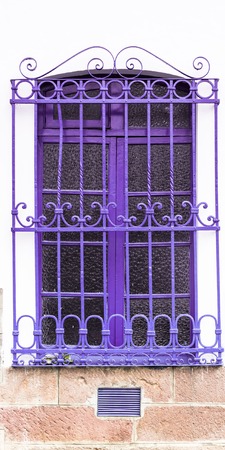 Caption of purple colored window and metal bars on white concrete buildingの写真素材