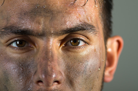 Closeup hispanic man dirty face eyes and nose caption looking to camera.の写真素材