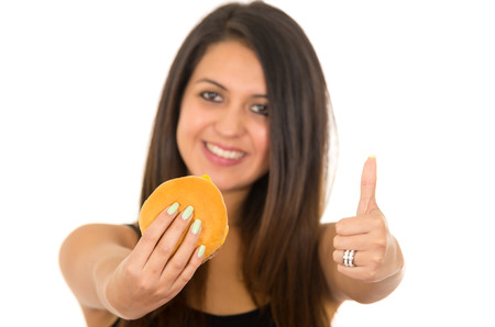 Hispanic brunette model holding up hamburger to camera and giving thumbs up, white background.の写真素材