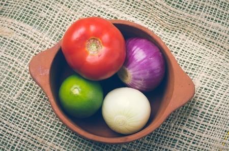 brightly colored tomato, onions with lemon in ceramic terracota bowl and hemp textile.の写真素材
