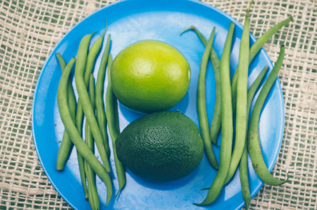 lime, avocado and green beans on blue plate with rustic background.