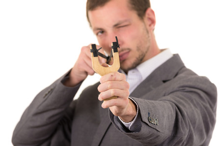 Handsome buisness man concentrated aiming a slingshot isolated over white background.の写真素材
