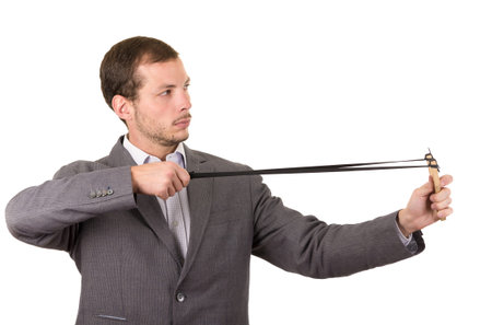 Handsome buisness man concentrated aiming a slingshot isolated over white background.の写真素材