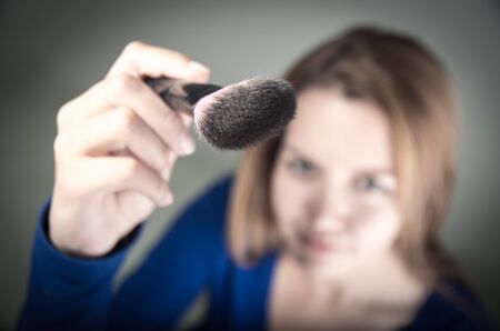 Beautiful young teen girl holding makeup brush, selective focusの写真素材
