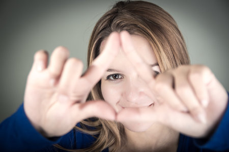 closeup portrait of cute young teen girl making a triangle with her fingers selective focus
