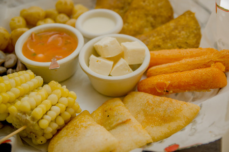 Closeup delicious food platter of typical latin foods such as corn, empanadas, abbas, cheese and salsas nicely arranged.の写真素材
