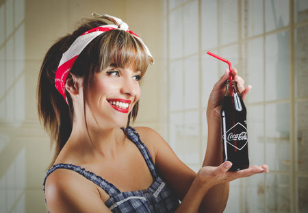 QUITO, ECUADOR - JULY 31, 2015: Beautiful retro girl holding an old vintage coca cola bottle