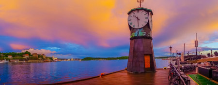OSLO, NORWAY - 8 JULY, 2015: Charming small clocktower located at Aker Brygge pier during sunset...