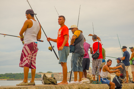 HAVANA, CUBA - AUGUST 30, 2015:  Local men fish on the sea in the city of Havana, Malecon quay. Fishing is a common hobby in Cuba.