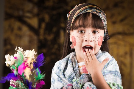 Cute little surprised girl dressed as a traditional finnish easter witch holding flowersの写真素材