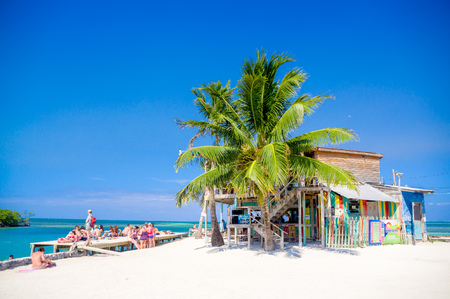 CAYE CAULKER, BELIZE - APRIL 10, 2014: Unknown touristis enjoying in colorful beach bar and wooden dock above turquoise waterのeditorial素材