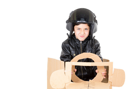 Adorable young boy dressed in pilot costume sitting in a cardboard car playing isolated over white background.の写真素材